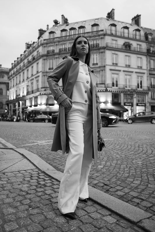 A woman standing on a street corner in front of a building