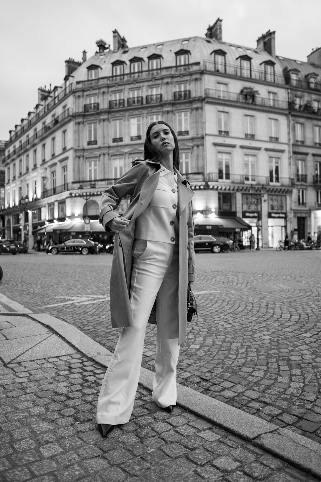 A woman standing on a street corner in front of a building
